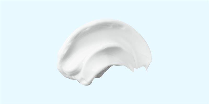 Das Bild zeigt eine Creme auf einem hellblauen Hintergrund an.