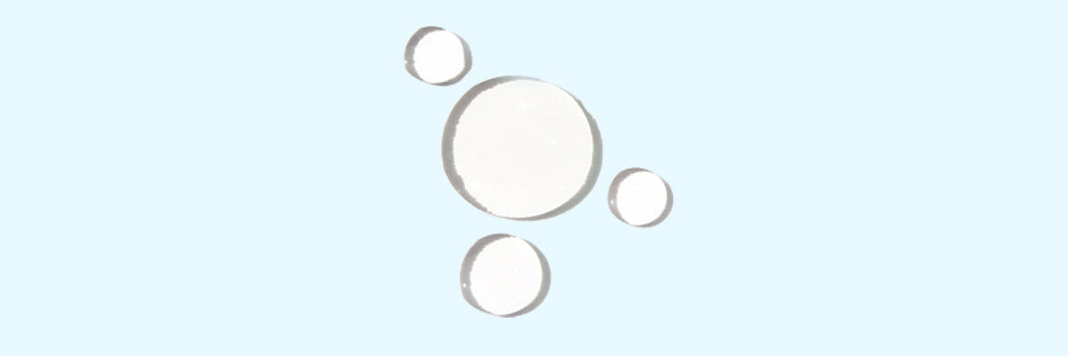 Das Bild zeigt eine paar Tropfen Flüssigkeit auf einem hellblauen Hintergrund an.