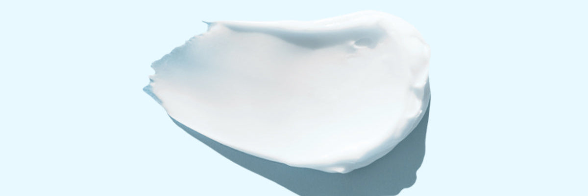 Das Bild zeigt eine Creme auf einem hellblauen Hintergrund an.
